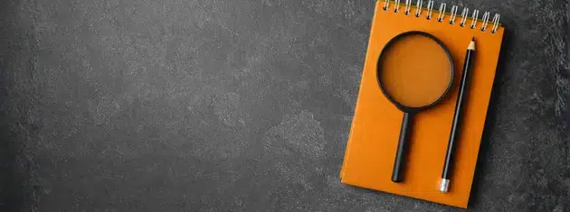 Pencil, magnifying glass, and a notebook, symbolizing content creation for marketing