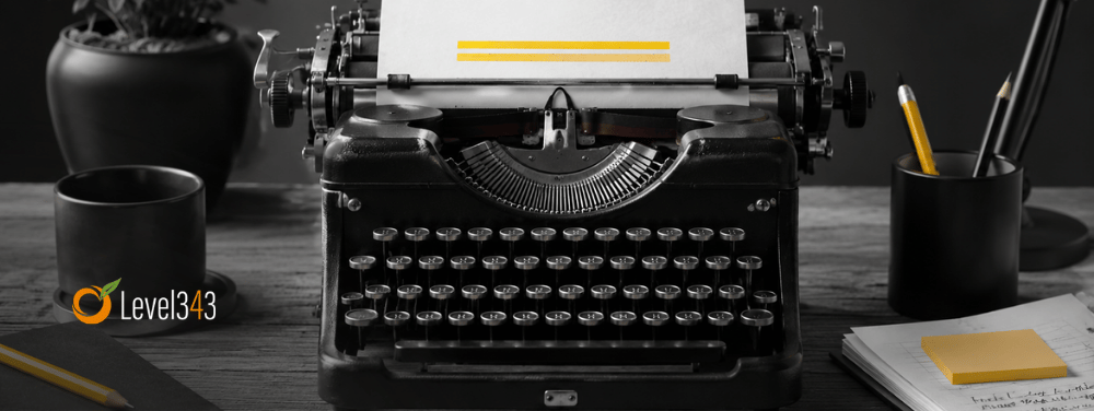 Black-and-white typewriter on a writer’s desk with yellow accents on the paper, pencil, sticky note, and lamp shade.