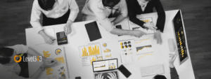 Overhead view of a marketing team reviewing analytics reports and dashboards, with grey and white tones accented by yellow chart highlights.