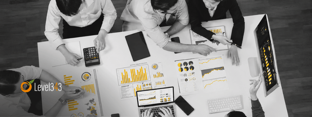 Overhead view of a marketing team reviewing analytics reports and dashboards, with grey and white tones accented by yellow chart highlights.