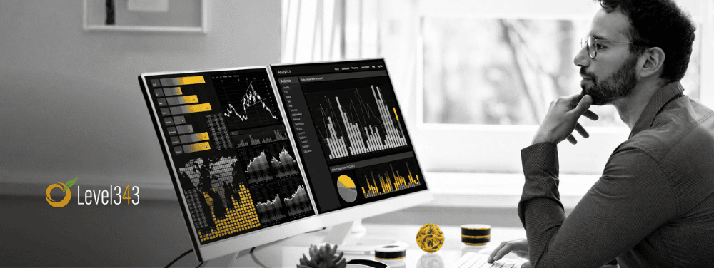 Focused analyst reviewing black-and-white marketing dashboards with yellow data highlights on dual monitors.