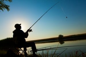silhouette of man fishing on lake