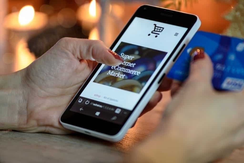 Person shopping via cellphone, holding credit card